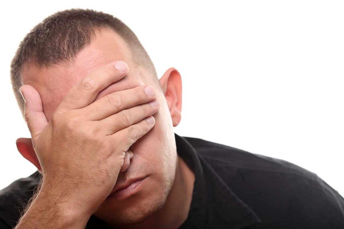 Mann hält mit der Hand sein Gesicht, Ausdruck von Frust oder Erschöpfung.